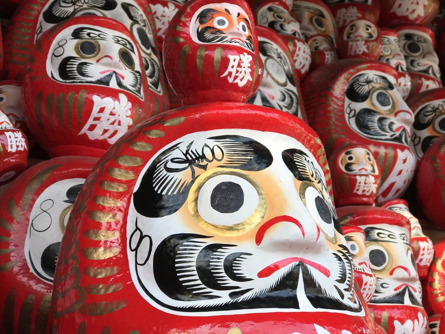 Rows of red daruma dolls at a temple