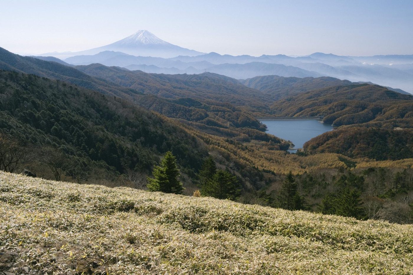Mount Fuji and a mountain lake under a blue haze